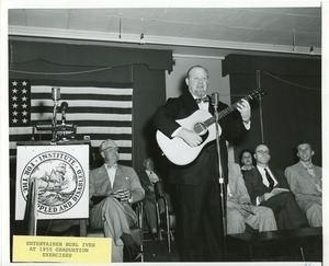 Burl Ives playing the guitar at graduation exercises