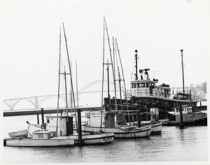 Boats by a dock with Yaquina Bay Bridge in the distance