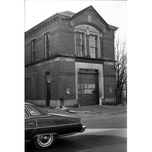 Image of 407 Dudley Street, Roxbury, Massachusetts, La Alianza Hispana's headquarters, with a car driving by in the left foreground.