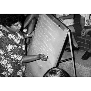 Woman tallying votes on a blackboard in the plaza following elections for Inquilinos Boricuas en Acción board members.