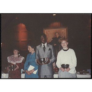 Three award recipients posing with their trophies while a woman looks off to the right during the "Recognition Dinner at Harvard Club"