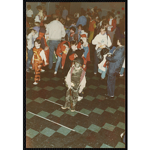 Children in Halloween costumes and adults gather at a Halloween party