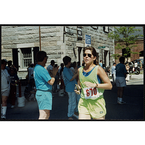 A woman finishes the Battle of Bunker Hill Road Race as race officials look on