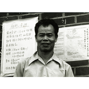 Portrait of Long Guang Huang standing in front of a brick wall in Chinatown