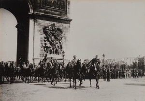 Street-level view of Marshal Foch and Marshal Joffre leading a military parade under the Arc de Triomphe, Paris