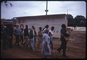 Guitarists leads a line of residents past a graffiti-covered wall in the Resurrection City encampment
