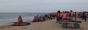 International Fund for Animal Welfare volunteers care for stranded dolphins lying on cushions near the water, with crowd looking on