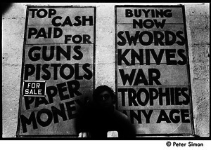 Kim Rosen standing in front of a sign at a curio store 'Top cash paid for guns...'