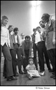 Staff of Cambridge Phoenix posing with a baby: Jean Grillo (left) ,Elliot Blinder (3rd from left), Robert Ventola (bending over), Jeffrey Tarter (2nd from right)