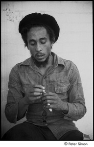 Bob Marley holding a joint the steps of his home