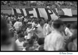Beatles fans during concert at Shea Stadium seated beneath a banner reading 'Help'