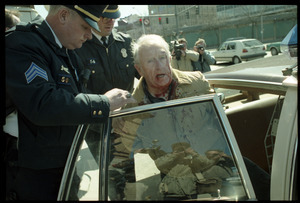 Elderly man with bloodied head (Wilfrid Lapierre) being arrested and put into patrol car by two policemen after protesting the banking crisis