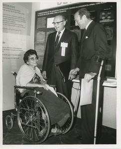 Charlotte Cohen in conversation with two men, one using forearm crutches