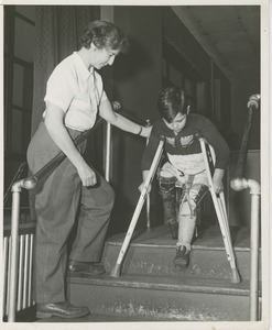 Boy walking down stairs with crutches and leg braces