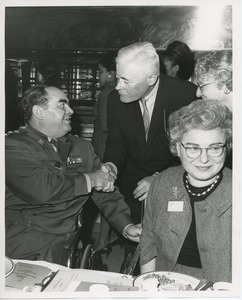 Hermann G. Place shaking hands with veteran in wheelchair at Thanksgiving celebration