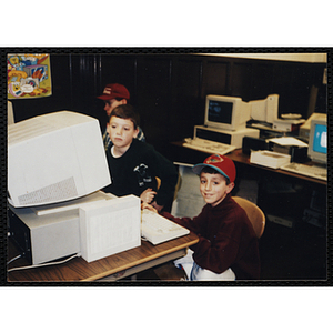 Two boys sit at a computer in a lab