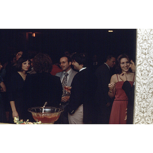 People stand around a punch bowl at an unidentified formal event