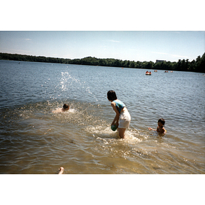 Young woman plays with two young children in a lake while attending a Chinese Progressive Association picnic
