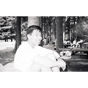 Young man sitting in a wooded picnic area