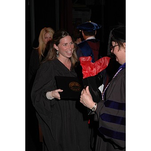 Faculty member presents student with certificate and gift bag at School of Nursing convocation