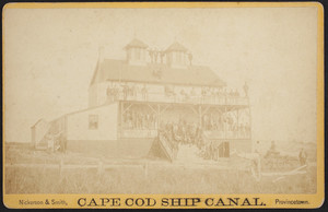 Cape Cod Ship Canal, cabinet card of an exterior view of a lodging house with men standing on the porches roof, possibly workers on the Cape Cod Canal.