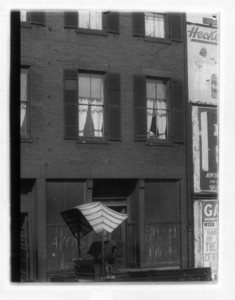 View of the corner of a building next to billboards with a wagon in the street, probably Dorchester Ave.