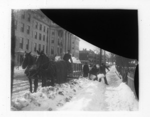 Workers shoveling snow into horse drawn wagon