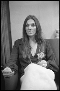 Judy Collins: three-quarter length portrait,seated in a chair with spray of flowers