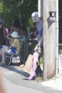 Parade goer in faux fishnet stockings leaning against a telephone pole : Provincetown Carnival parade