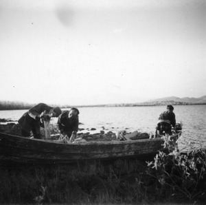 Three Sami men launching a boat on Lake Torneträsk