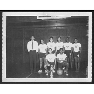 Group portrait of boys' basketball team in gym below hoop