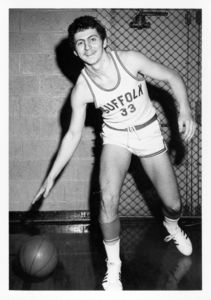 Suffolk University men's basketball player Chris Tsiotos (#33) dribbles a basketball in a posed photograph for the camera, 1976