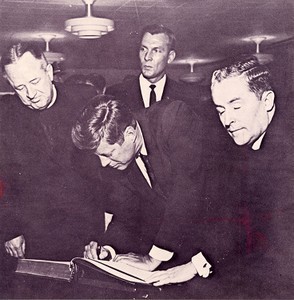 Kennedy, John F. (John Fitzgerald) signing guest book at Boston College