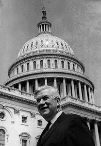 Head and shoulders shot of Thomas P. O'Neill, smiling, in front of U.S. Capitol