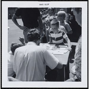 Boys standing in line at the registration table for a Boys' Club Freckle King Contest