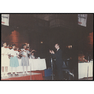 Three girls playing violin and a man conducting at the "Recognition Dinner at Harvard Club"