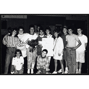 A dozen Boys & Girls Club members posing for a group picture with "Thanks for 10 [?]" sign and flowers