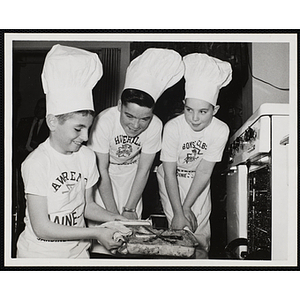 Three members of the Tom Pappas Chefs' Club pose next to an open oven