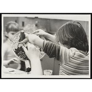 A girl in a kitchen uses a masher to crush berries