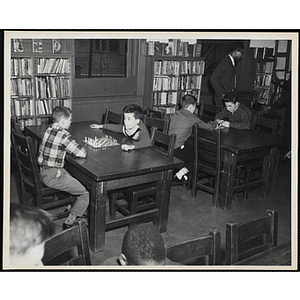 Pairs of boys play chess in a library reading room