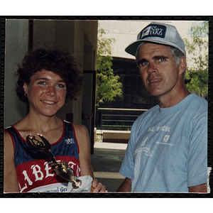 Runner Martha Perkins accepts a trophy from a man during the Battle of Bunker Hill Road Race