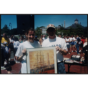 Executive Director Jerry Steimel (right) and a woman pose with a framed print at the Battle of Bunker Hill Road Race