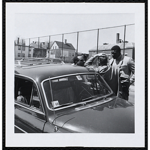 Four men talk as they stand next to a car at the Roxbury Road Race