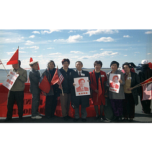 Members of the Chinese Progressive Association and others hold posters and flags for an event at Boston Logan Airport to welcome Zhu Rongji, premier of the People's Republic of China