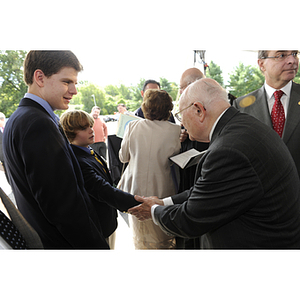 Dr. George J. Kostas shakes hands with a young boy at the groundbreaking ceremony for the George J. Kostas Research Institute for Homeland Security