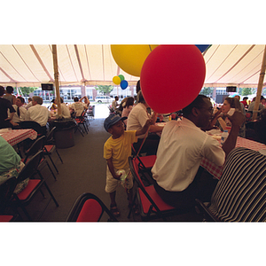 People celebrating and eating food under a large tent