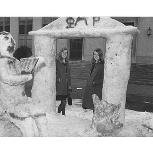 Two women stand under a snow sculpture at the Winter Carnival