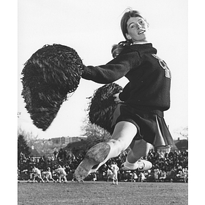 Cheerleader with pompoms jumping on sidelines of a football game