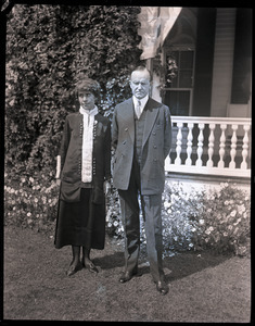 Calvin and Grace Coolidge standing in front of a house