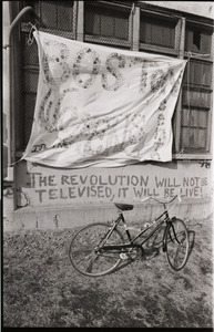 Women's occupation of the Architectural Technology Workshop, Harvard University: bicycle in front of banner for "Boston Women's Center" and graffiti "The revolution will not be televised, it will be live!"